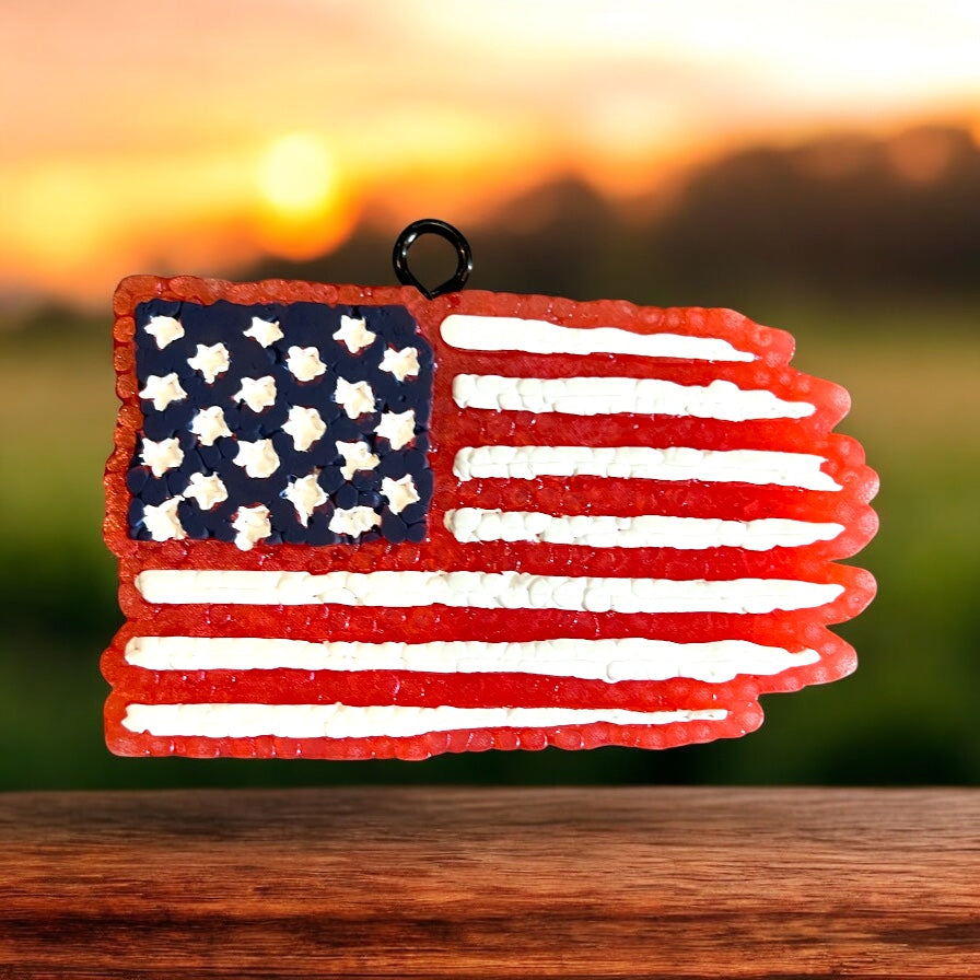 American flag ornament on a wooden surface with a sunset background