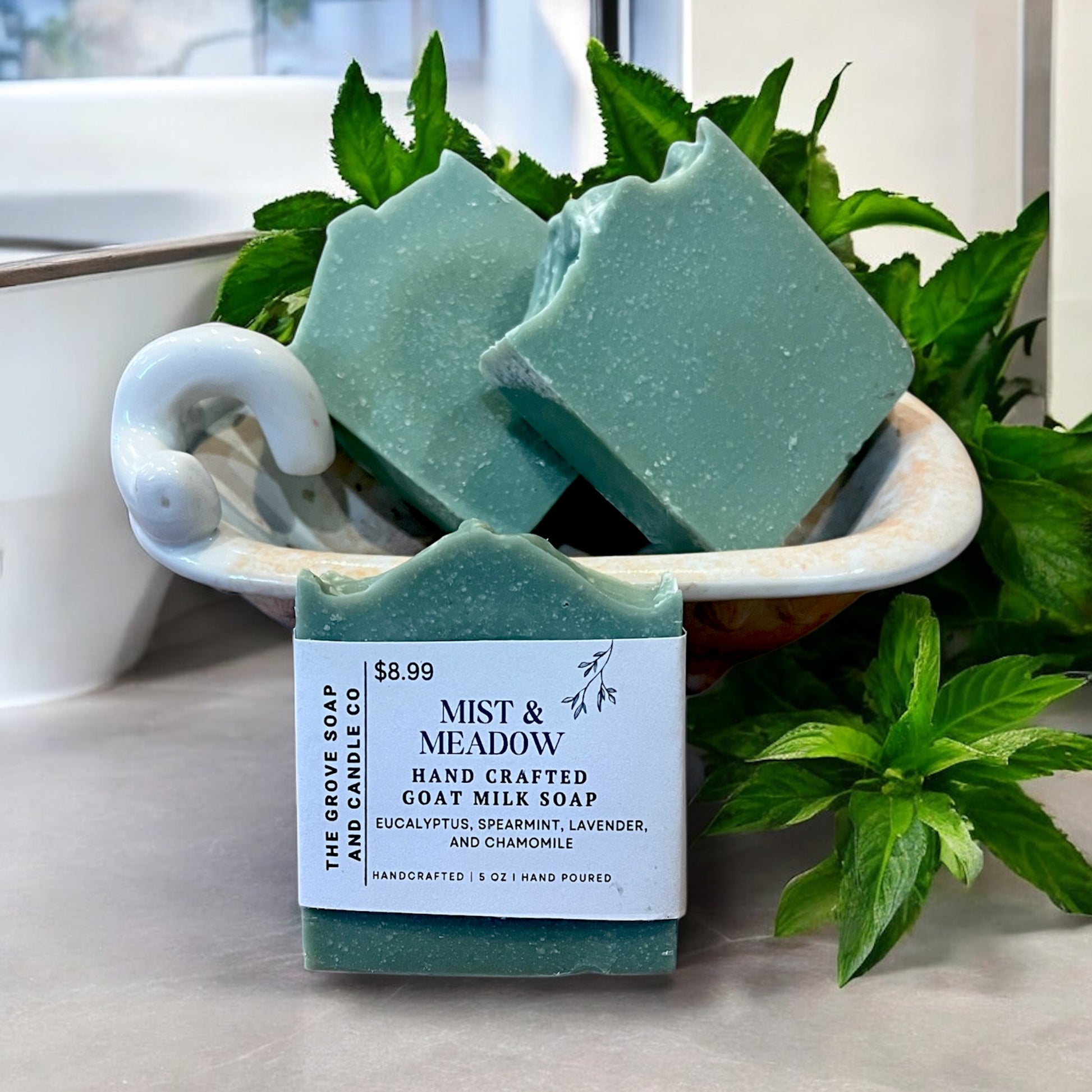 Mist and Meadow Goat Milk Artesian Soap displayed in a tub in a bathroom. Highlighting the spearmint fragrance of the soap.