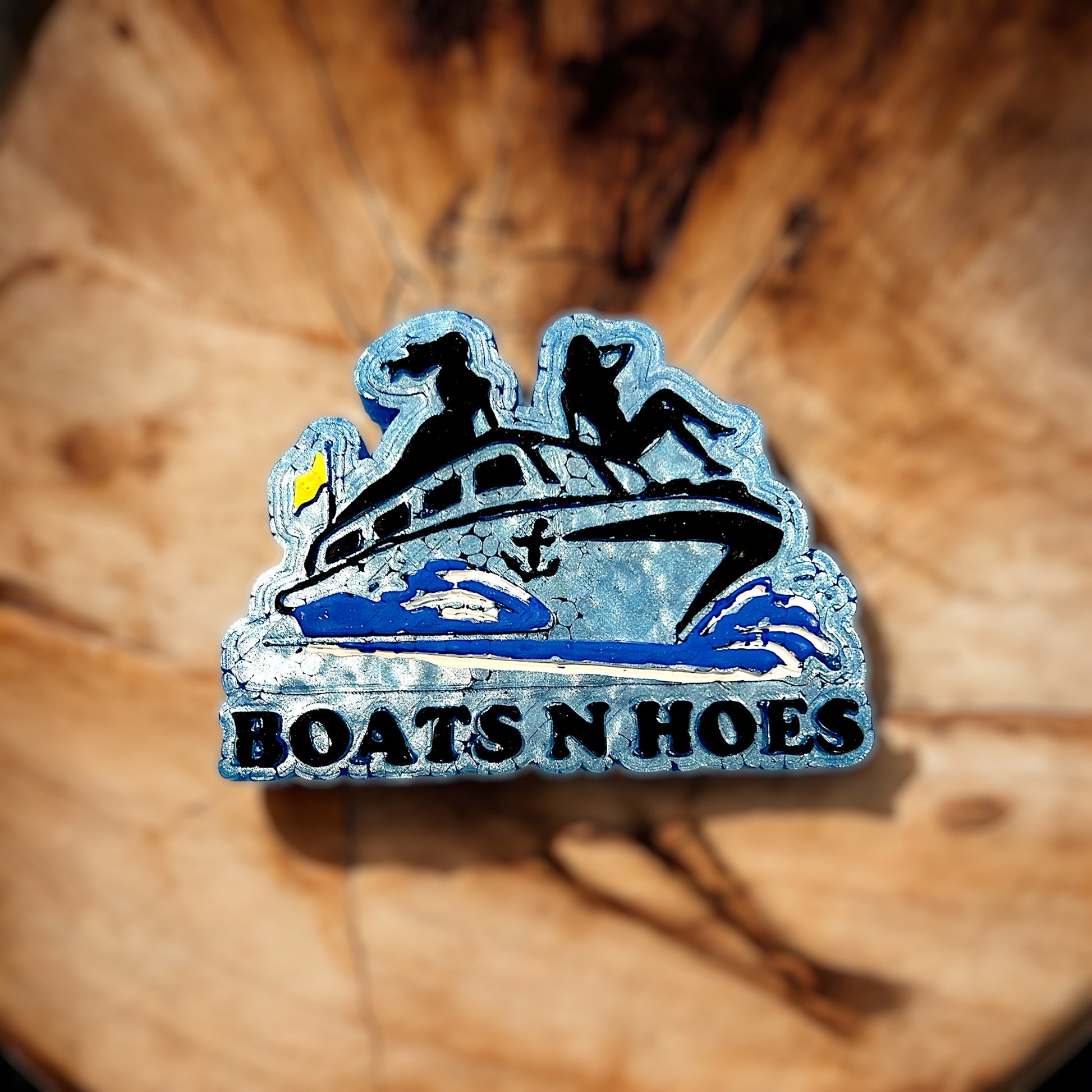 'BOATS N HOES' text on a blue yacht placed on a wooden surface