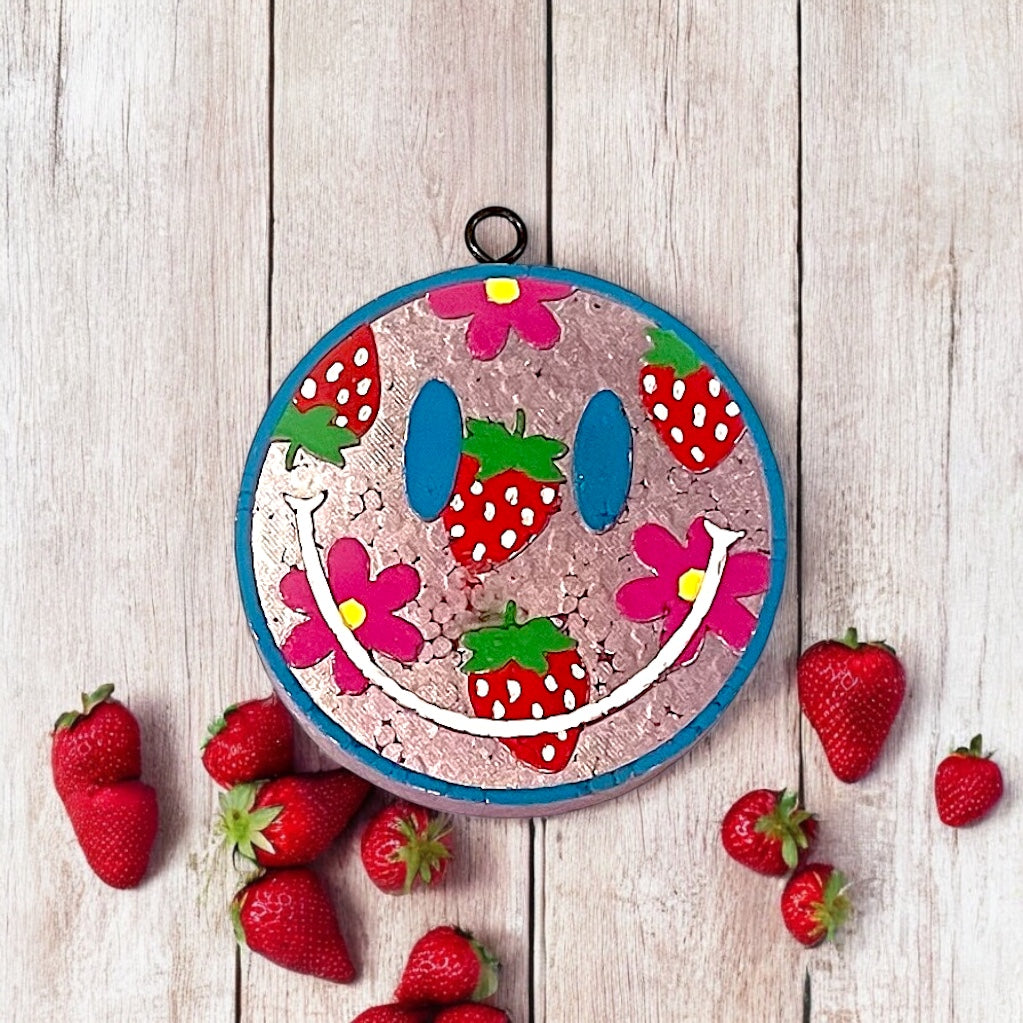 Decorative smiley face design car freshie and strawberries on a wooden surface