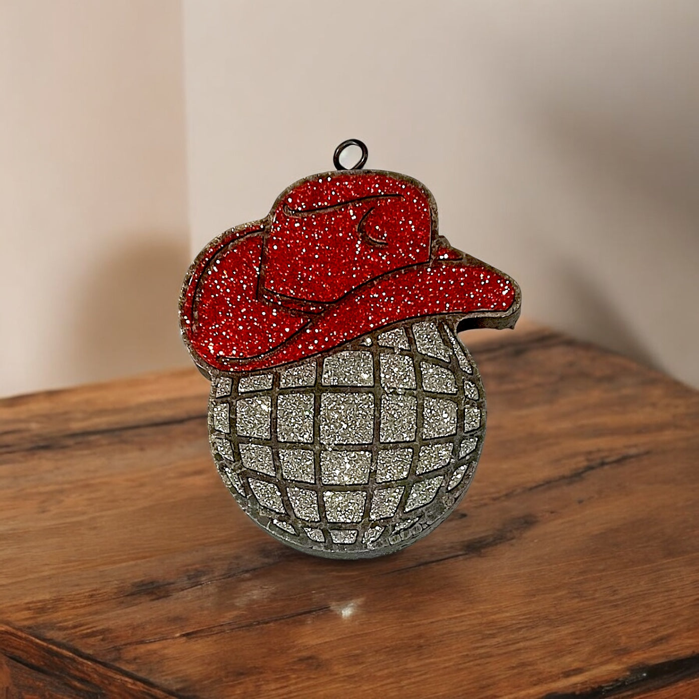 Decorative western car freshie with red top and silver base on a wooden surface