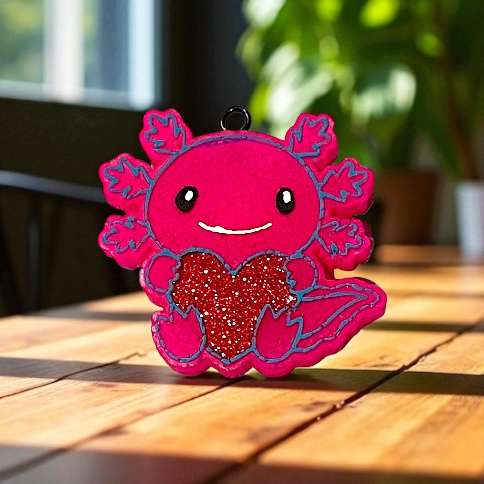 Pink axolotl car freshie with a red heart on a wooden surface