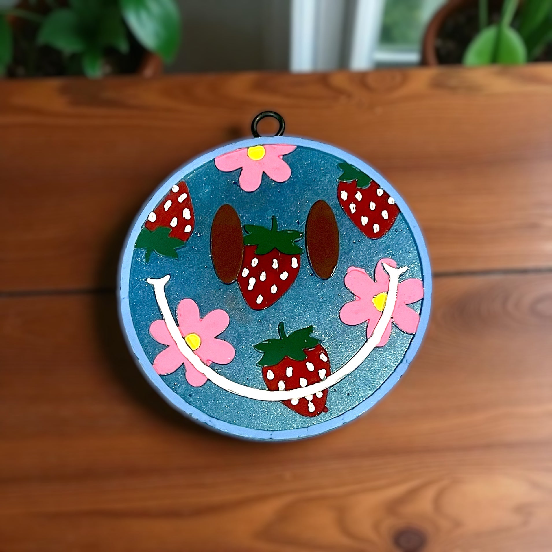Decorative circular  smiley face scented car accessory with strawberries design on a wooden surface