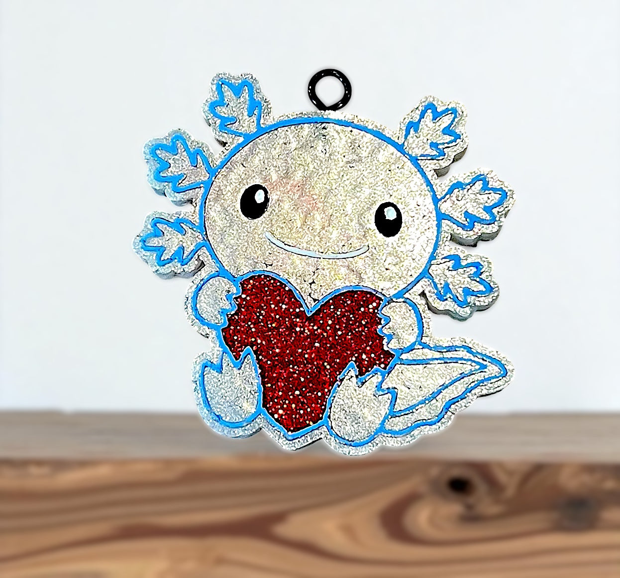 Decorative axolotl charm with a red heart on a white background