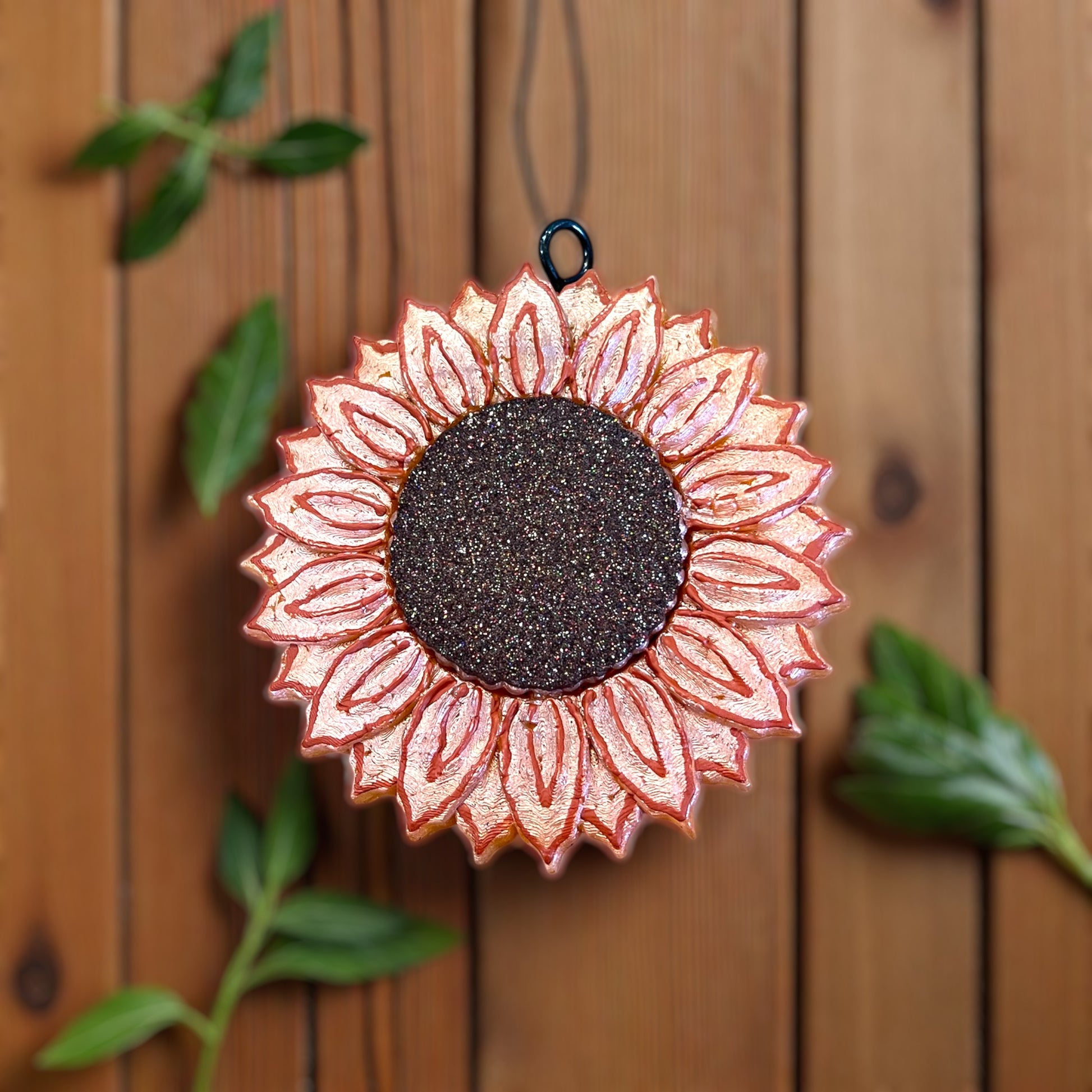 Decorative sunflower-shaped tangerine colored car accessory with glittery center on a wooden background