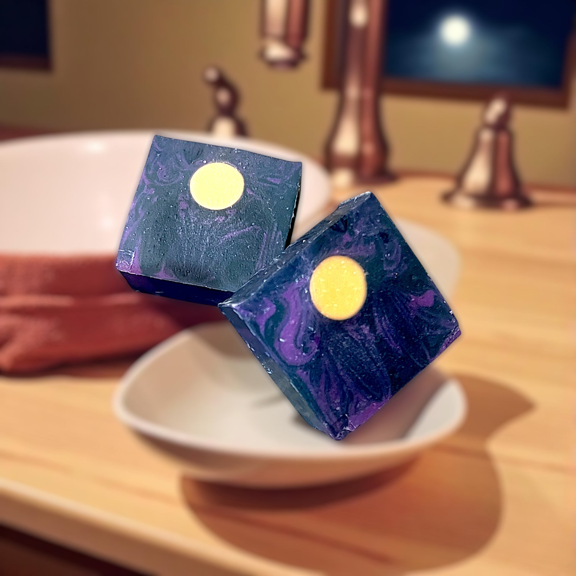 Two bars of Enchanted Moonlight goat milk soap with a starry night design on a white plate.