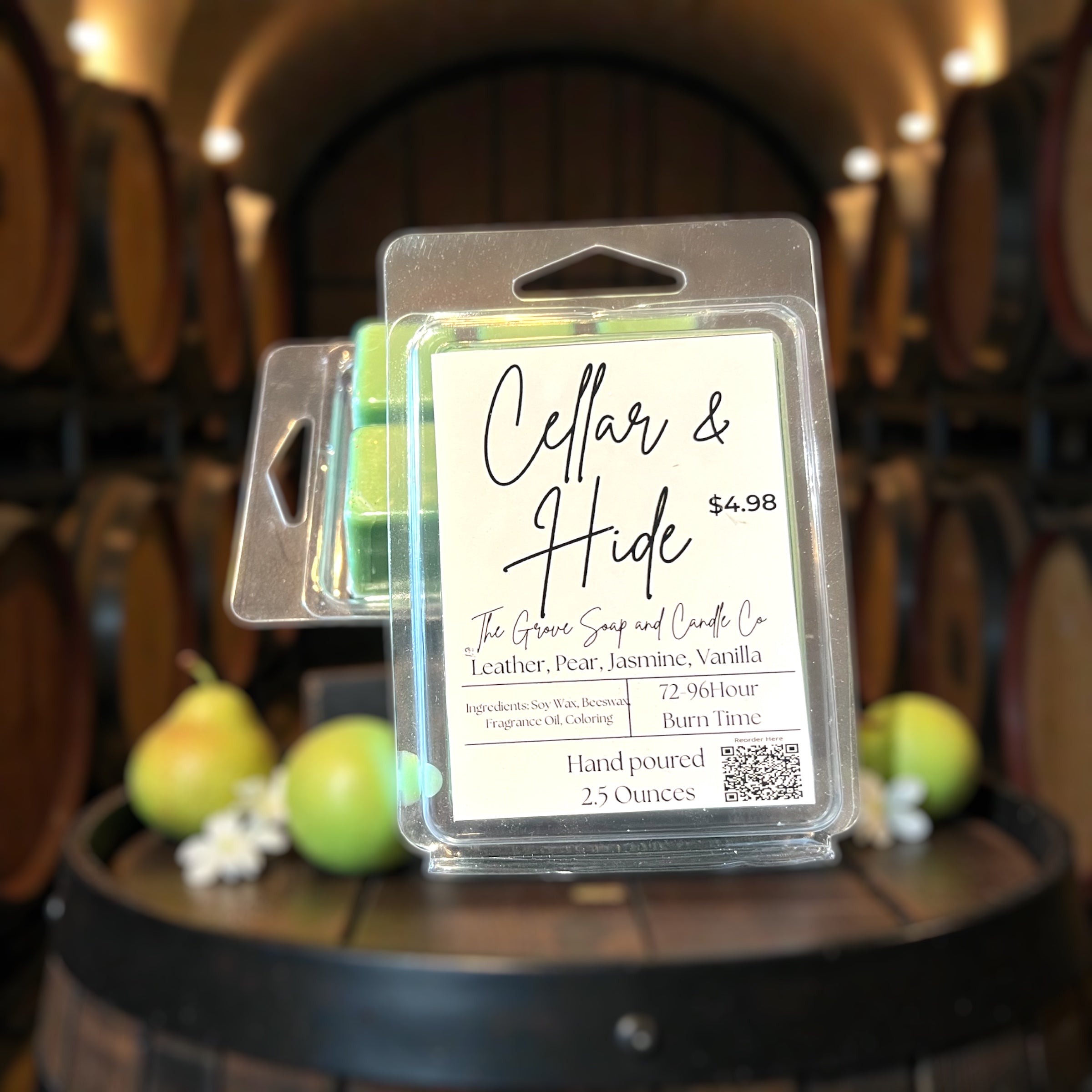 Packaged Wax Melts showing the label Cellar & Hide with the scent profile and ingredients. Sitting on a wine barrel with pears and jasmine. 