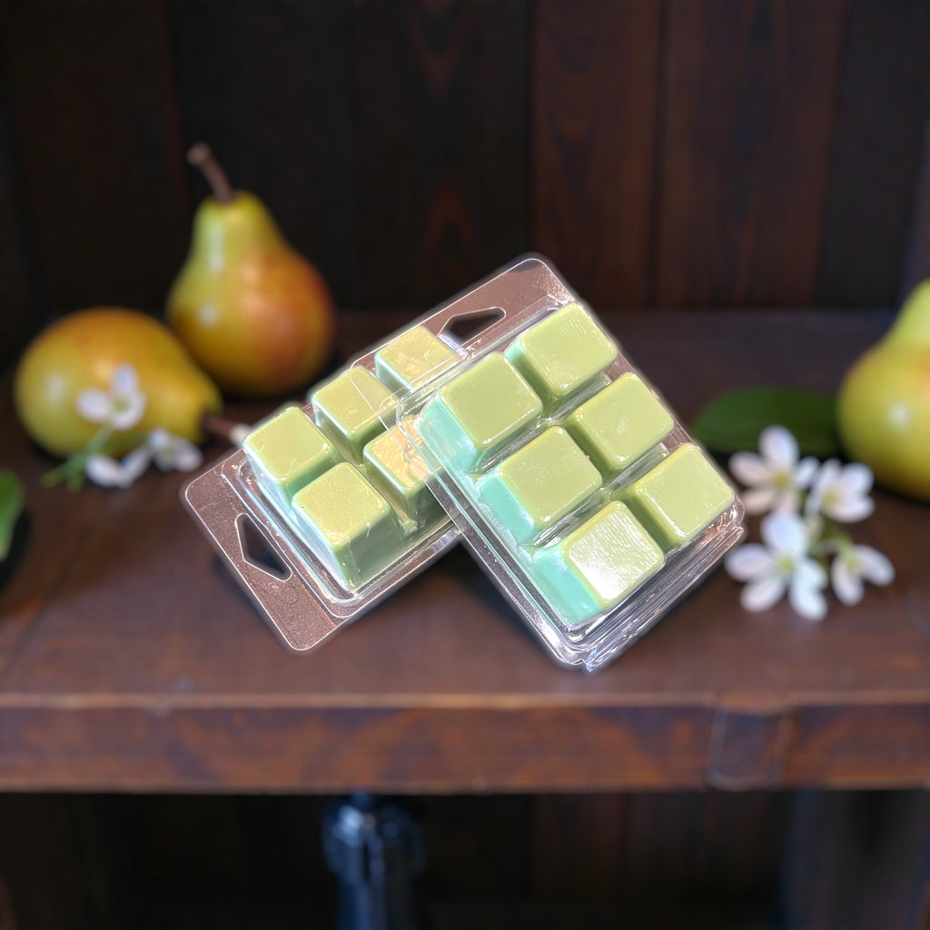 Two packs of green wax melts showing the color of Cellar & Hide. Surrounded by pears and jasmine. 