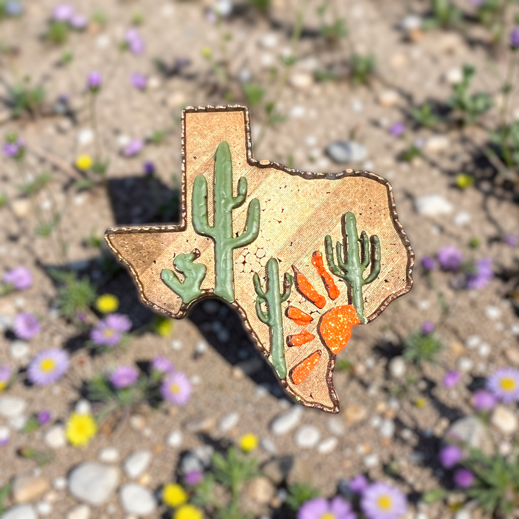 Brown texas shaped car freshie with green cactus and an orange setting sun. 