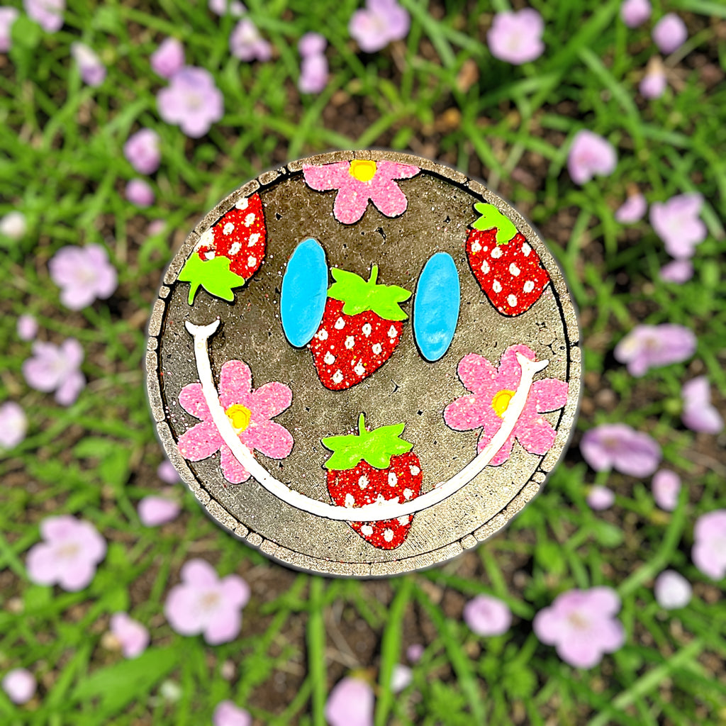 Black Strawberry Patch Car freshie with red glittered strawberries and pink glittered flowers. All on green grass surrounded by spring pink flowers. 