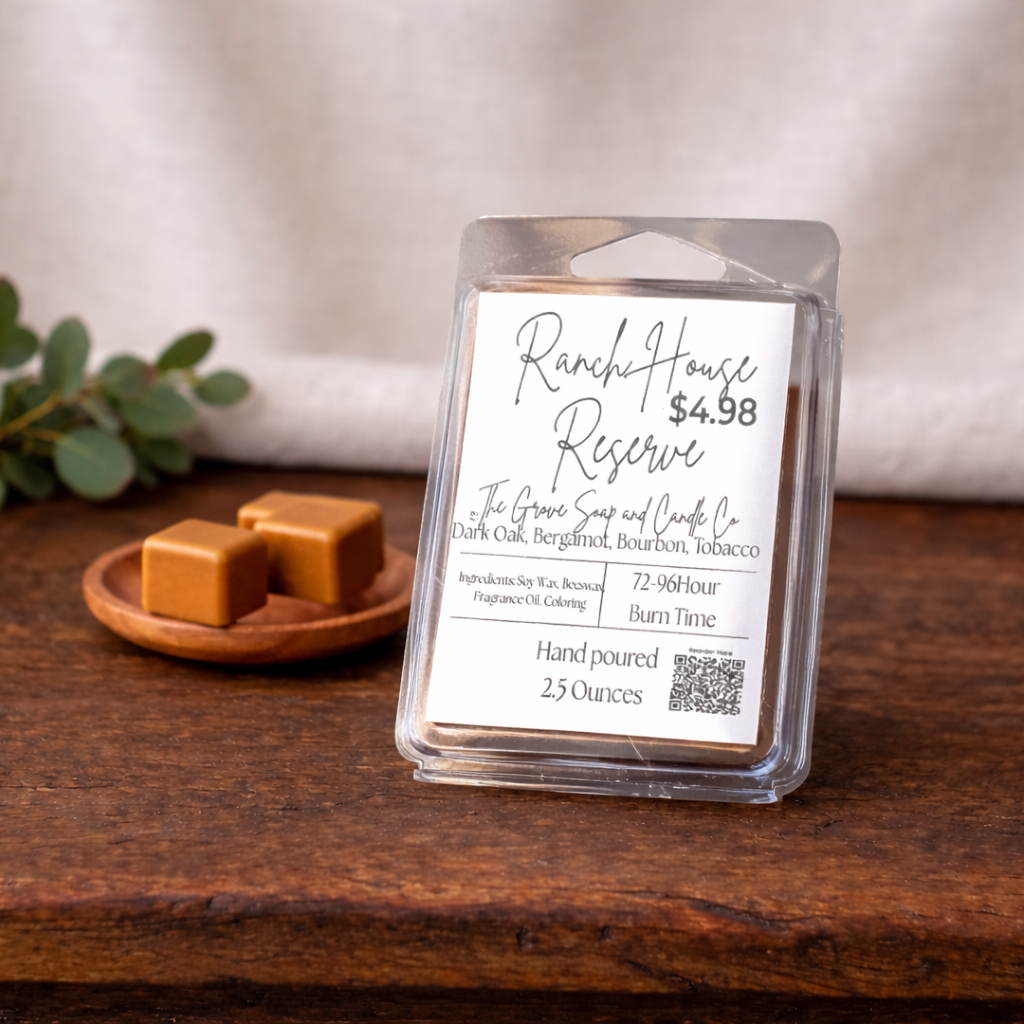 Ranch House Reserve Wax Melts. A blend of dark oak, bergamot, bourbon, and tobacco. Sitting on a wooden table with a small tray of brown wax melts to show the color of these melts. White linen background.