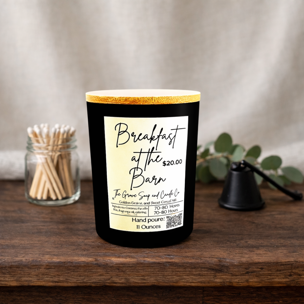 Breakfast at the Barn Candle sitting on a rustic wooden table with a linen background. Black matte jar with a wooden lid. Clear bottle of matches and a black candle snuffer. 