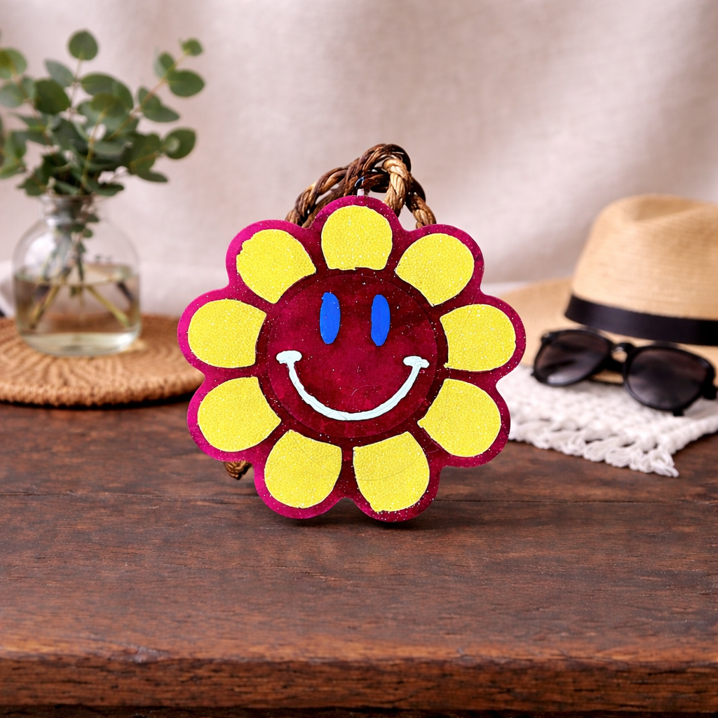 Bright pink smiley face car freshie with yellow glitter petals. 