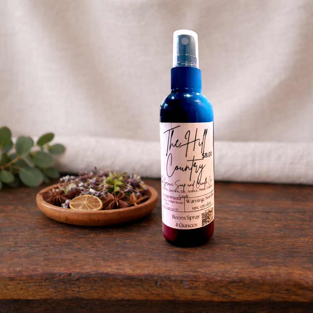 The Hill Country Room Spray in a black bottle on a wooden table with a linen background. 