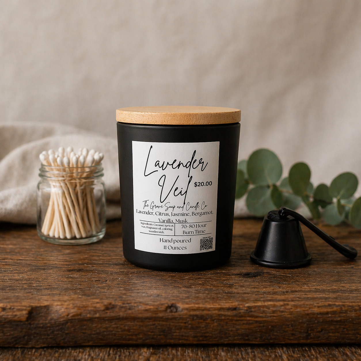 Lavender Veil Candle with wooden lid and label on a wooden surface with a neutral background. A custom exclusive blend of lavender, citrus, jasmine, bergamot, vanilla, and musk