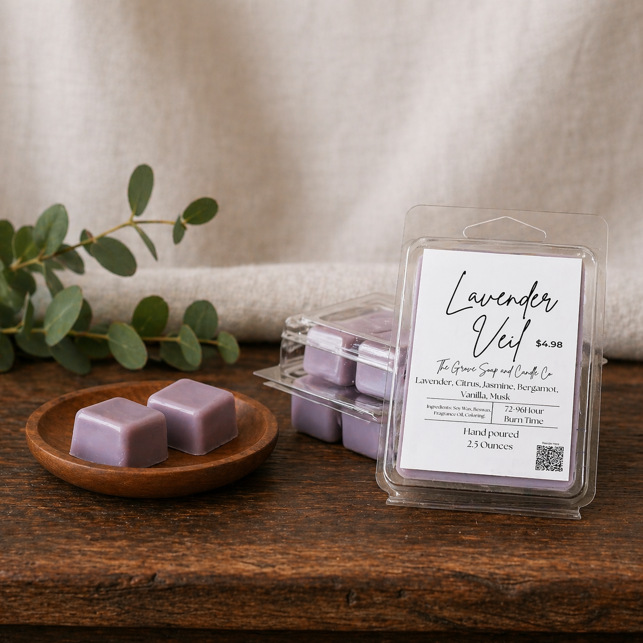 Lavender Veil wax melts in a wooden dish with packaging on a wooden surface. An exclusive custom blend of lavender, citrus, jasmine, bergamot, vanilla, and musk