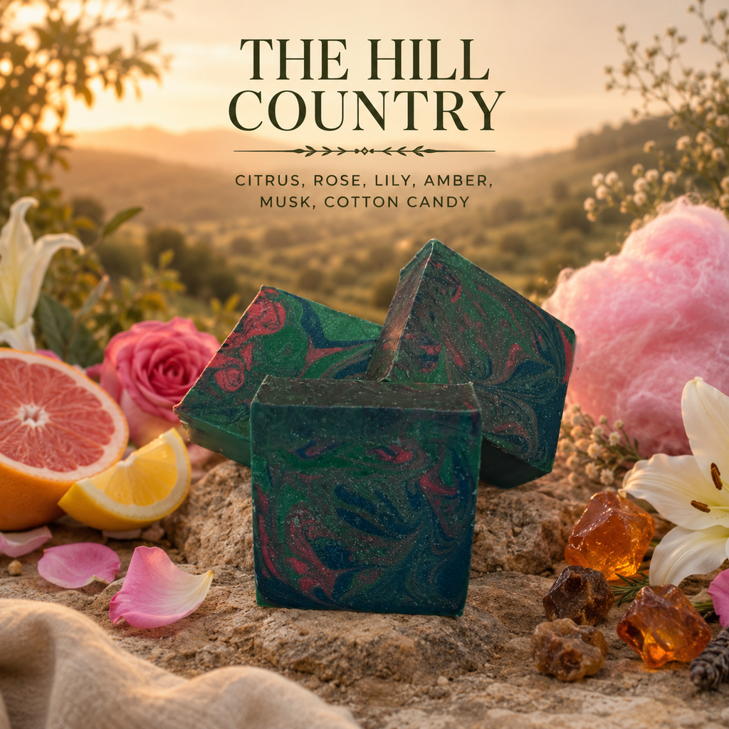 Decorative soap with 'The Hill Country' branding surrounded by flowers and fruits in a natural setting.