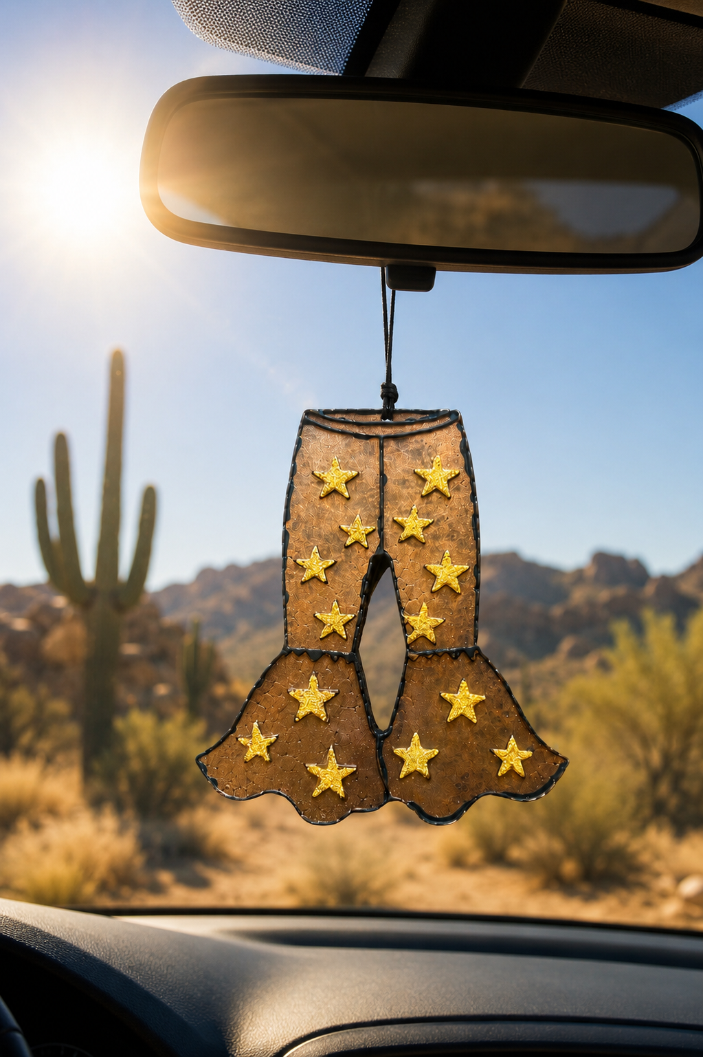 Fancy pants western bellbottom car freshie hanging from the car mirror with a desert background