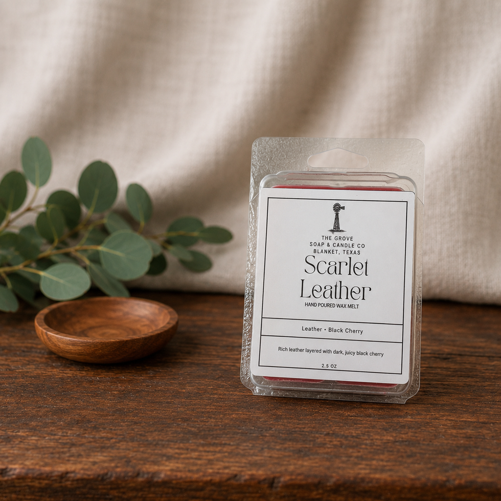 Scarlet Leather wax melts sitting on a wooden table with a linen background. Shows the product label and scent profile