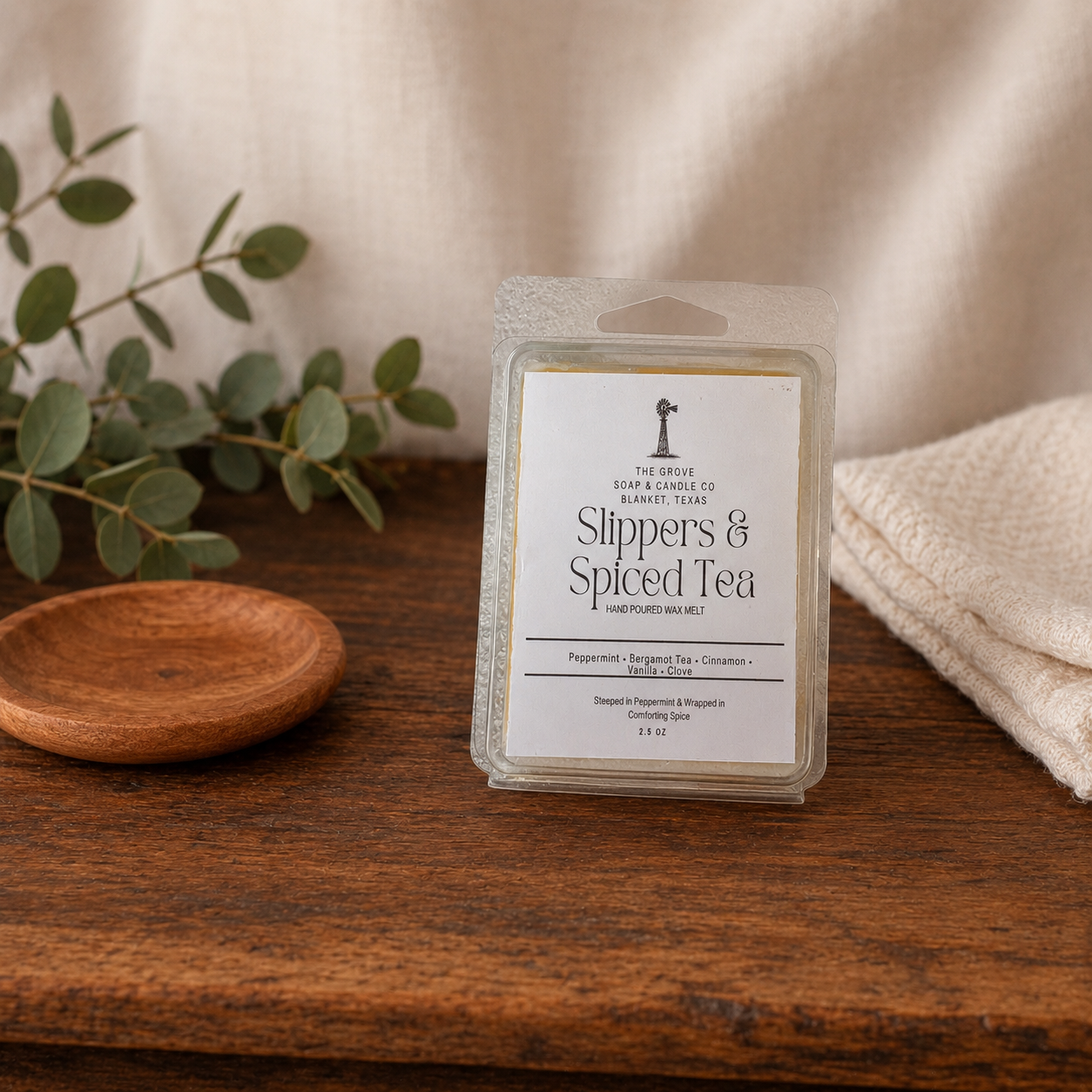 Slippers & Spiced Tea Wax Melts sitting on a wooden table with a linen background. Showing the labeling and scent profile