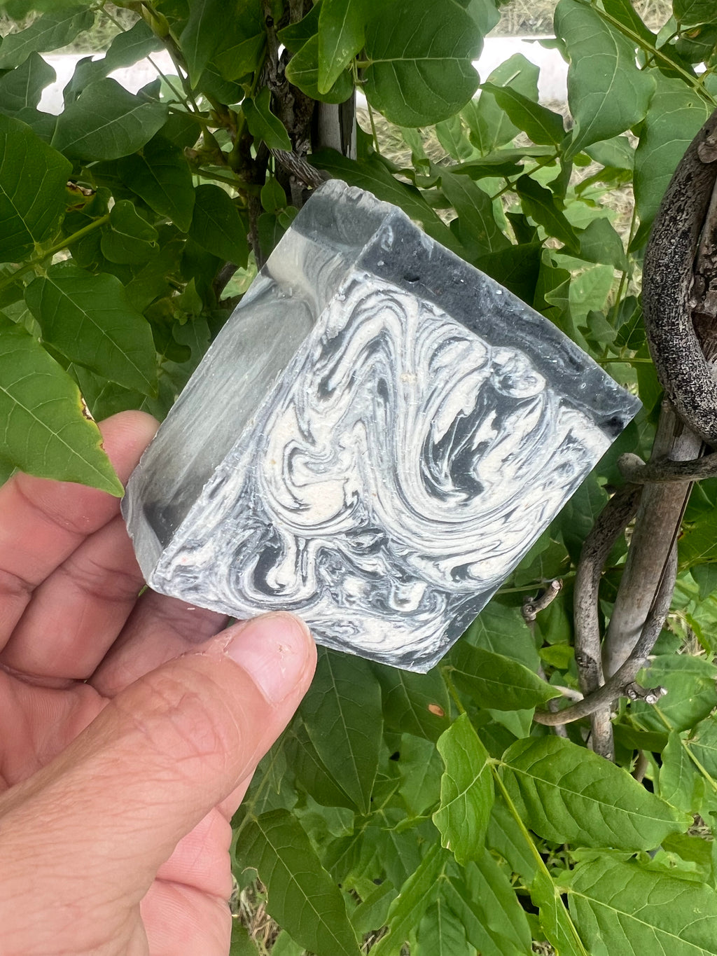 Close-up of textured handmade soap bar labeled Black Sea. Showcasing the artesian technique of swirling soap, the texture, and thickness of the bar. 