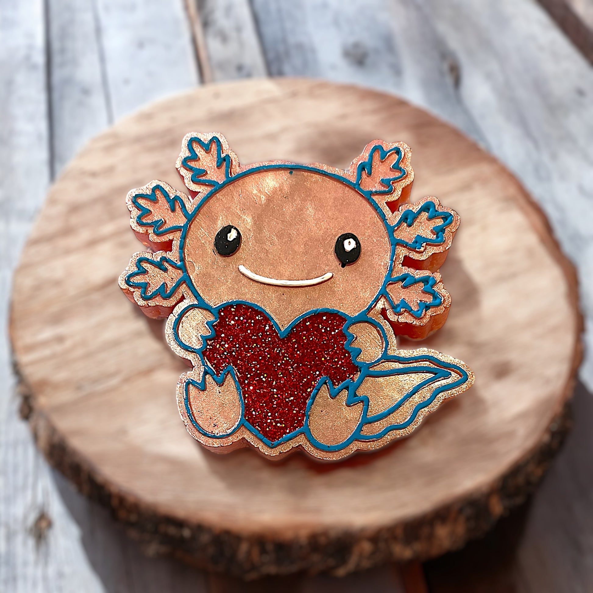 Peach axolotl aroma bead car accessory with a red heart on a wooden surface