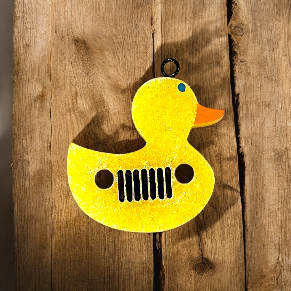 Yellow rubber duck jaroma car decor with a grill design on a wooden background