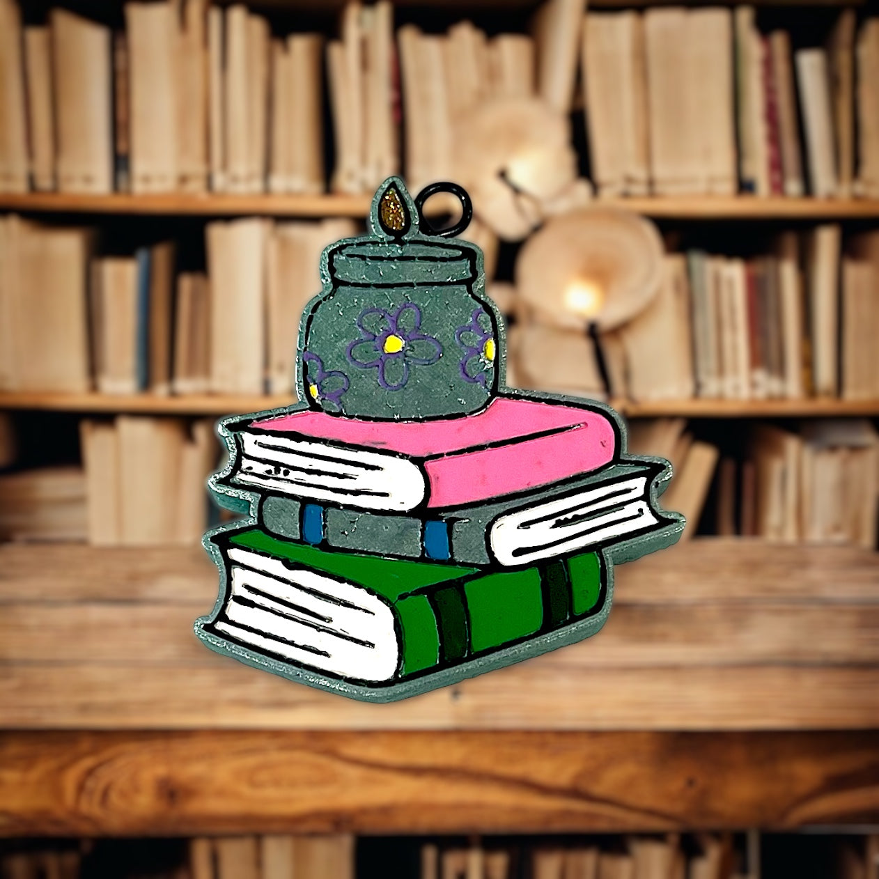 Colorful book-shaped car freshie with a jar on top against a bookshelf background