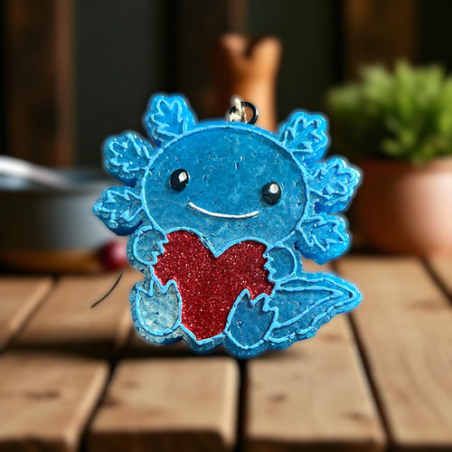 Blue axolotl car freshie with a red heart on a wooden surface
