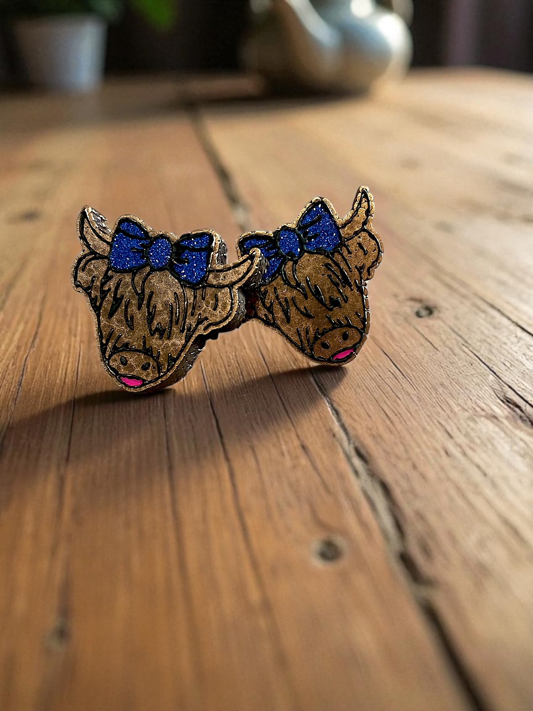 Bull skull vent clips with blue glittered bows on a wooden surface