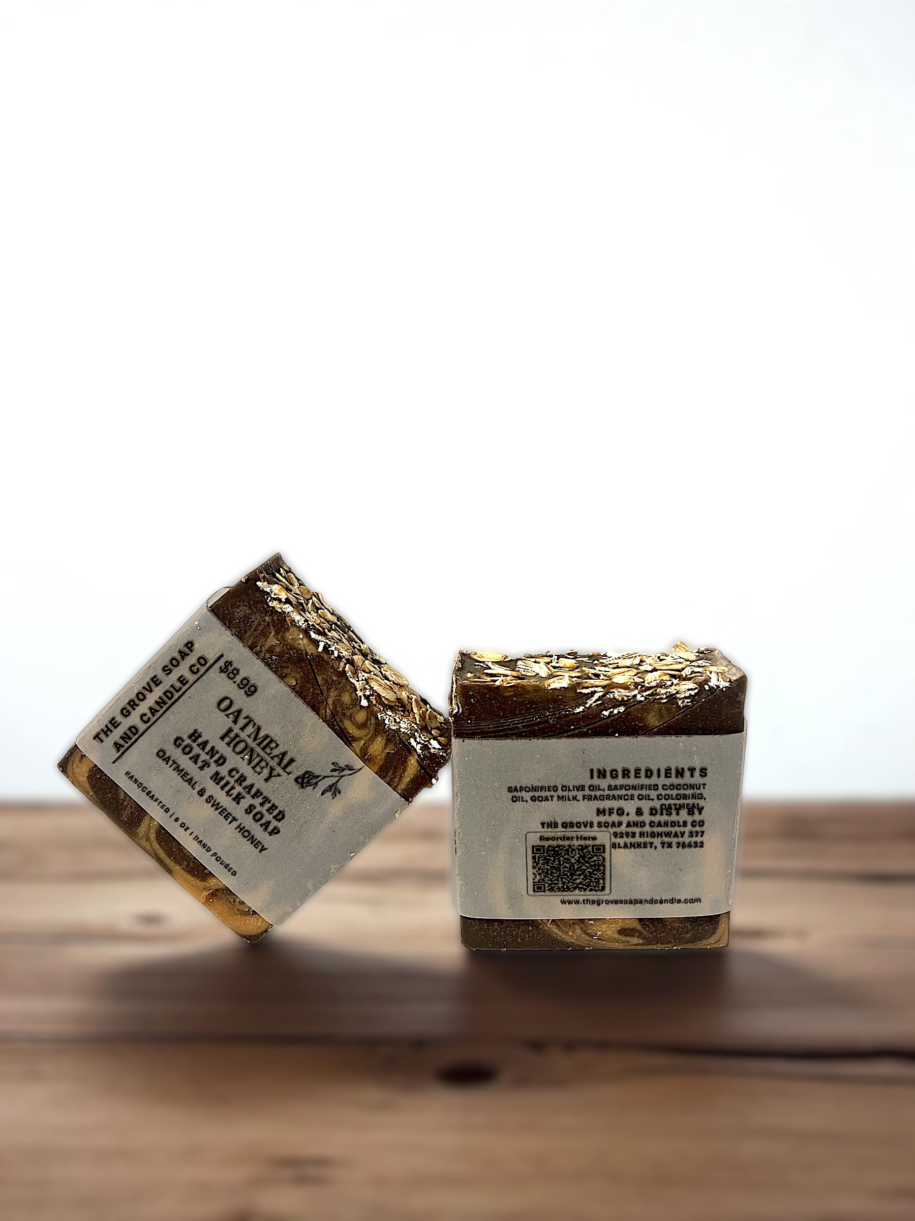 Two bars of soap with labels on a wooden surface. Shows the ingredients of this bar of goat milk soap. 