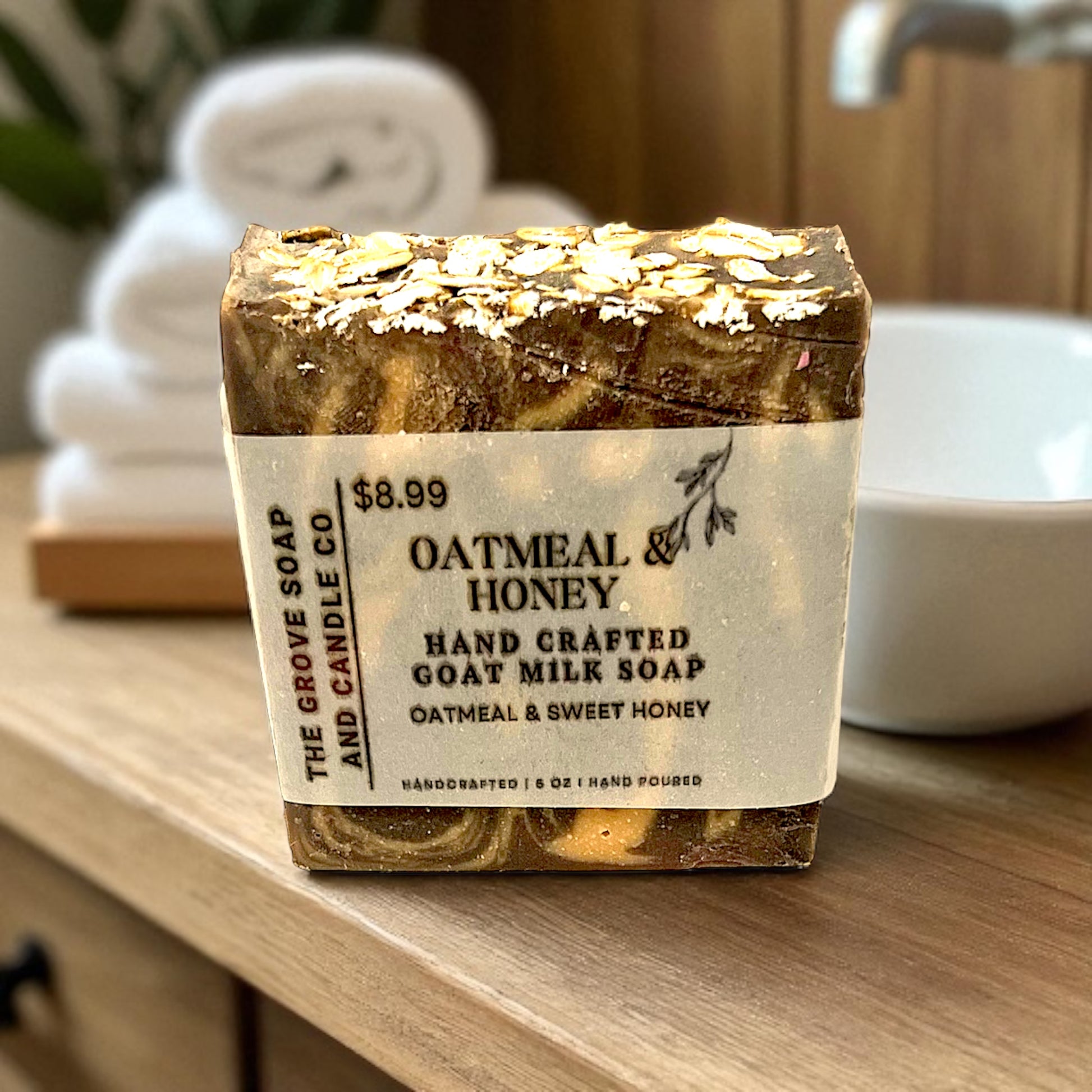 Oatmeal & Honey handcrafted goat milk soap on a wooden surface with a blurred background. Close up photo of the product brand label. 