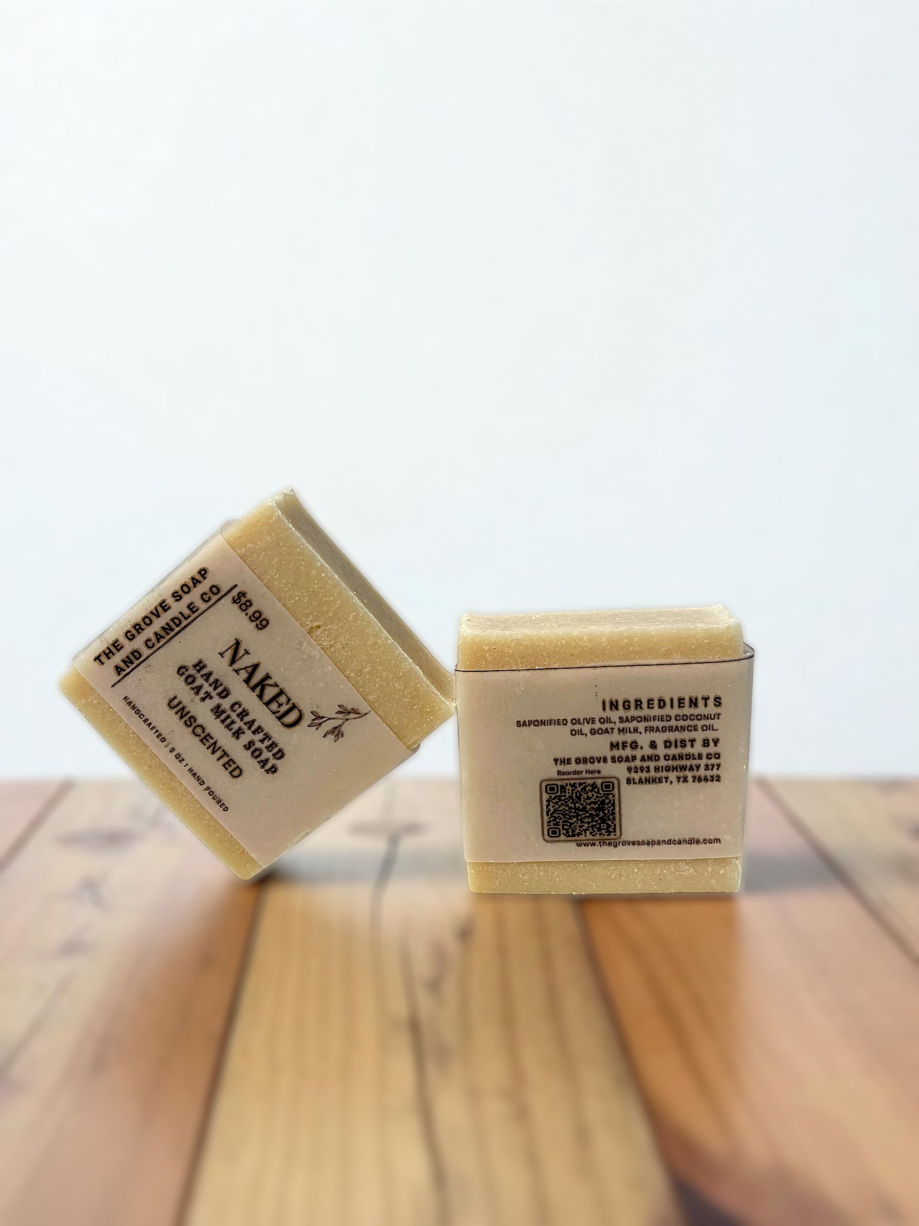 Two bars of soap with labels on a wooden surface showing the ingredients used to product this bar. 