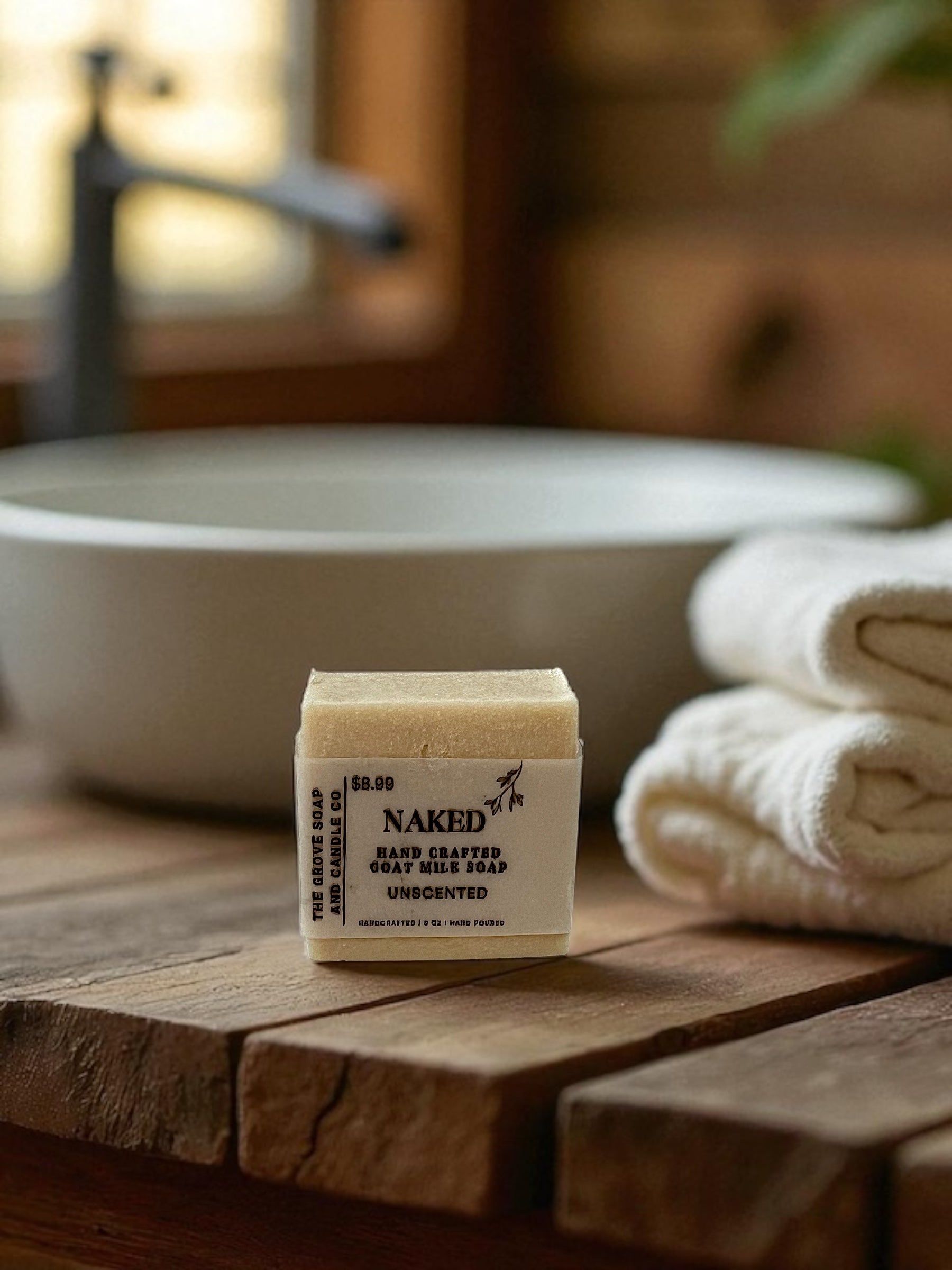 Bar of Naked soap on a wooden surface with a blurred bathroom background in a bathroom. Shows the product branding and labeling. 