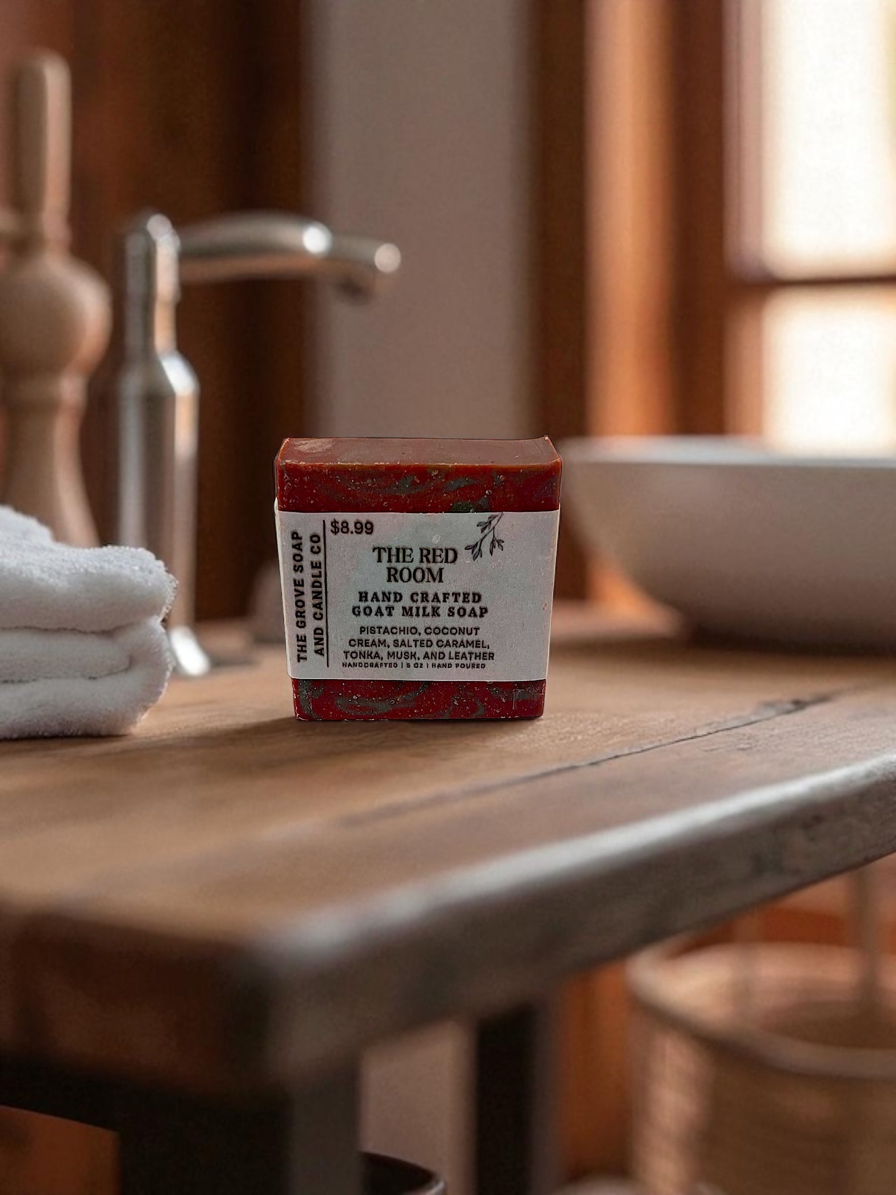 Bar of soap on a wooden surface with a blurred bathroom background. Shows the branding and packing for The Grove Soap and Candle Co. 