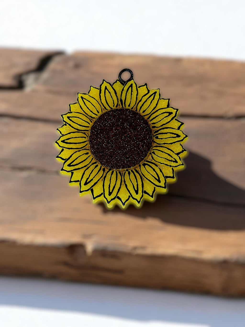 Yellow sunflower-shaped sunflower car freshie on a wooden surface
