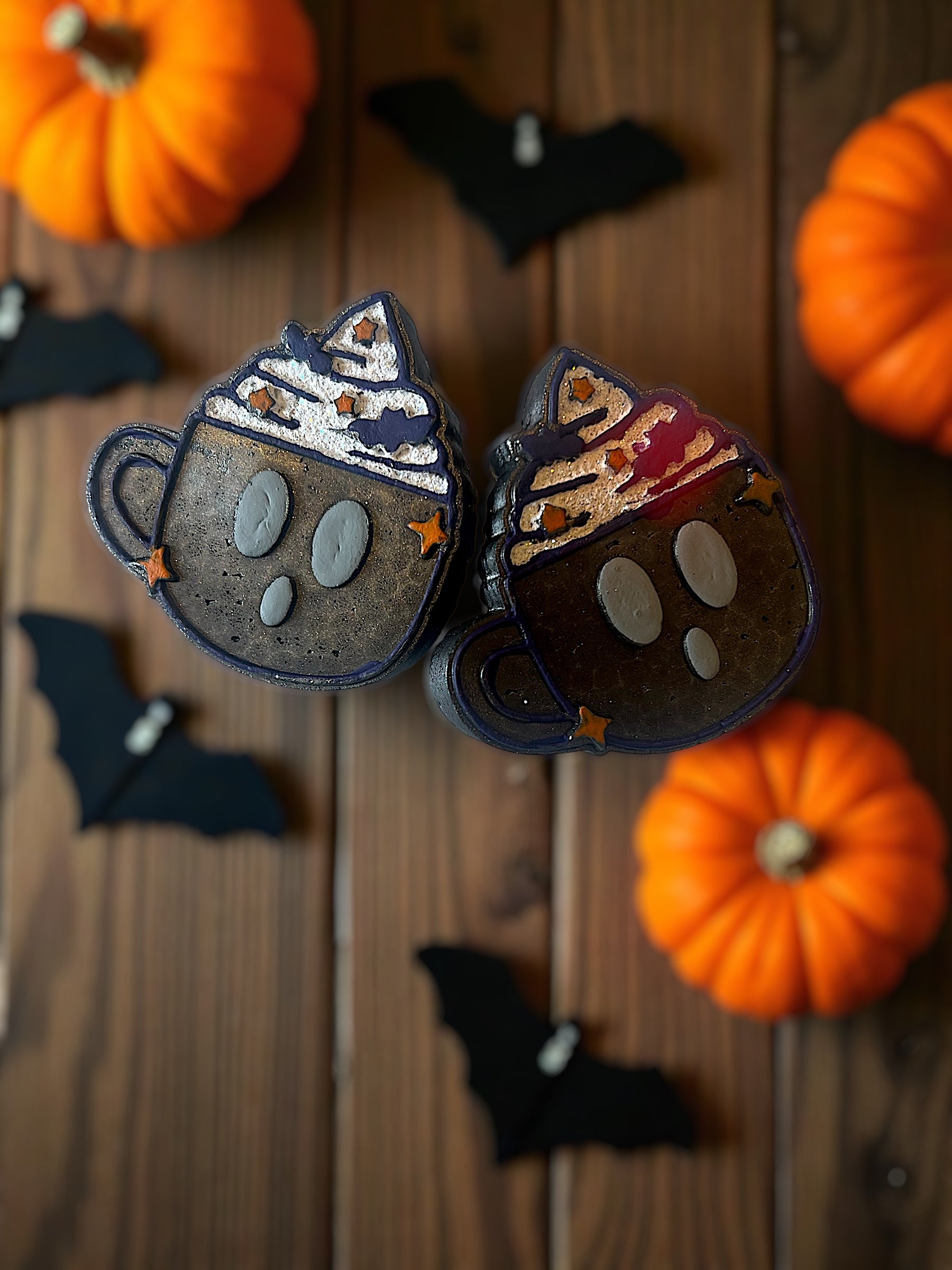 Halloween-themed black coffee cup vent clips with pumpkins and bats on a wooden surface