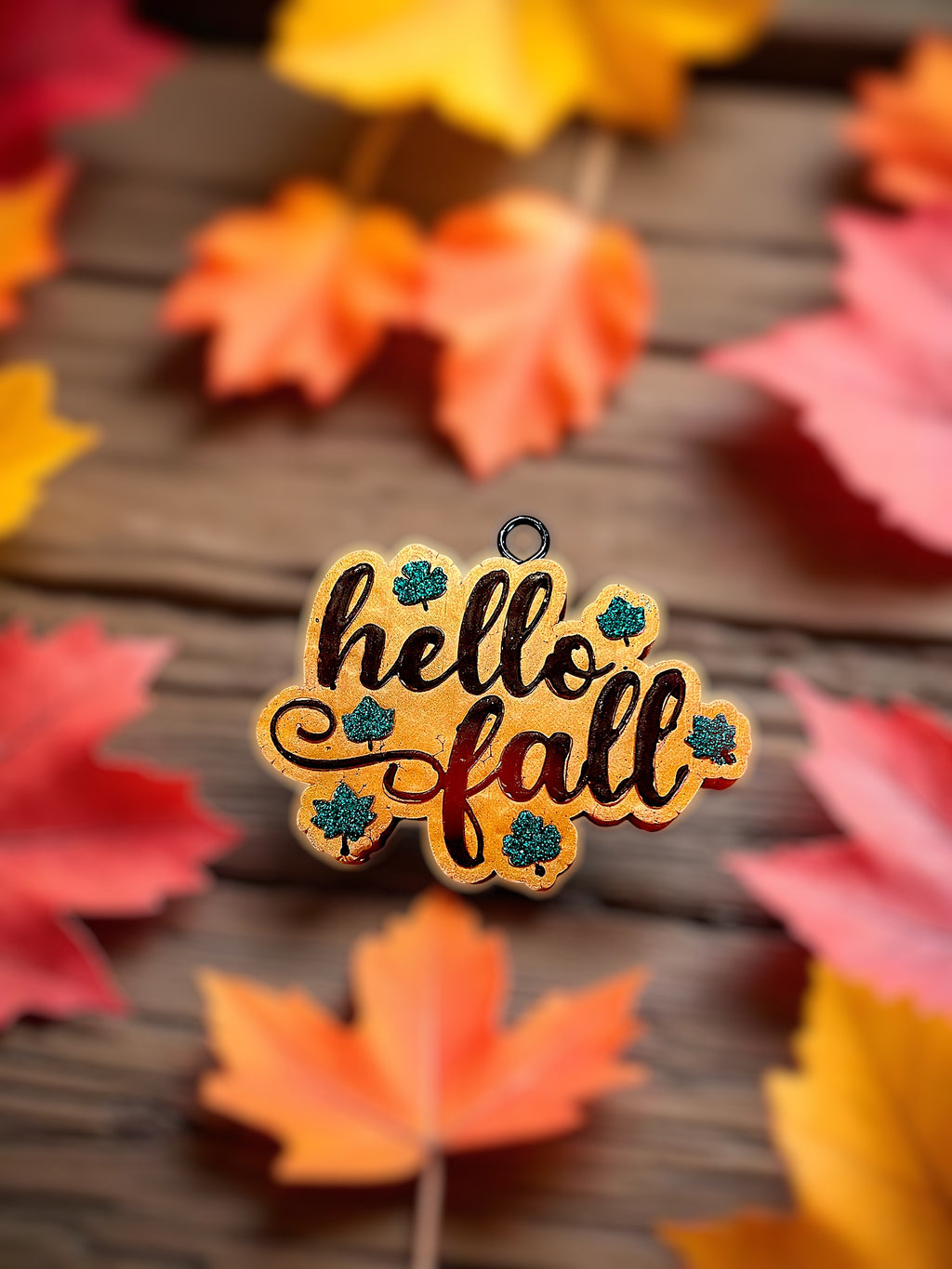 Autumn-themed 'hello fall' car freshie with colorful leaves on a wooden surface.