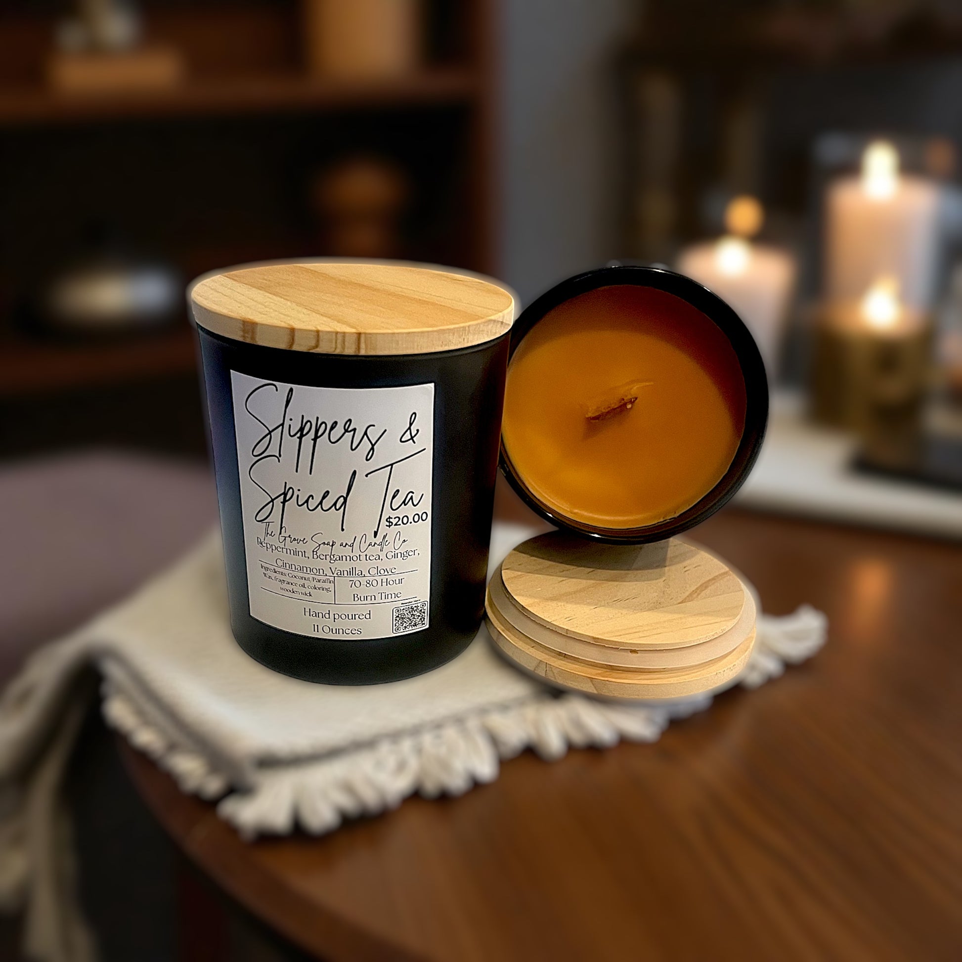 Candle with wooden lid and label on a wooden surface. Showing the product description of Slippers and Spiced Tea. 