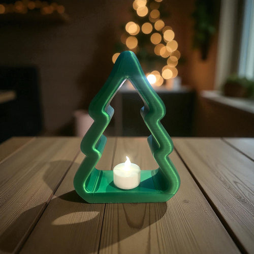 Green Christmas tree-shaped Tealight candle holder with a lit candle on a wooden table, blurred lights in the background.