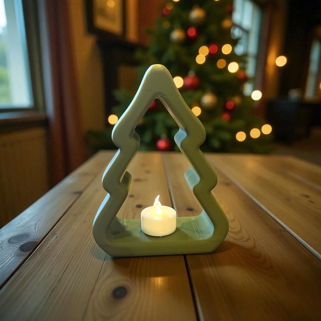 Green decorative Tealight holder with a lit candle on a wooden table, Christmas tree in the background