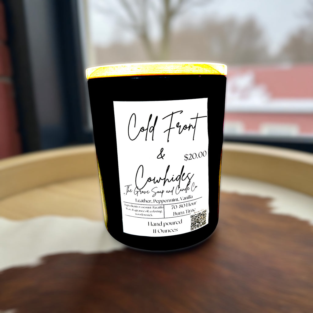 Candle with a label Cold Front & Cowhide on a wooden surface, featuring 'Cold Front & Cowhides' branding.