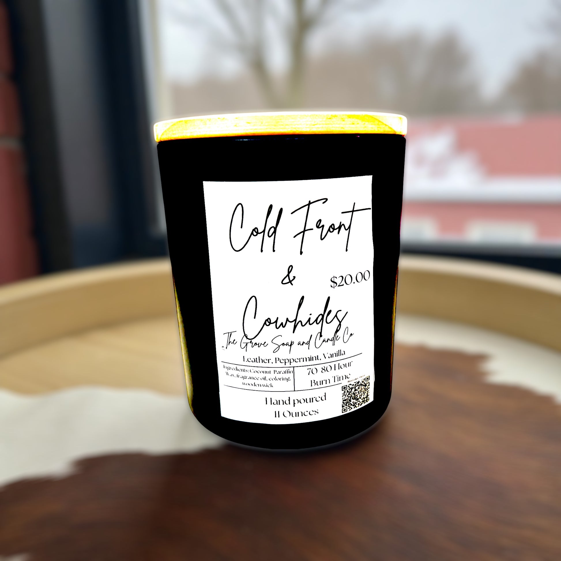 Candle with a label Cold Front & Cowhide on a wooden surface, featuring 'Cold Front & Cowhides' branding.