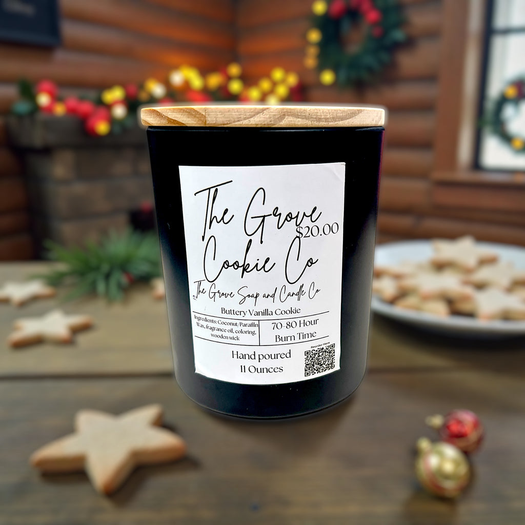 Candle with 'The Grove Cookie Co' label on a wooden surface with cookies and Christmas decorations in the background